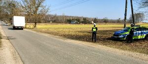 Policjanci stoją przy drodze i mierzą prędkość.