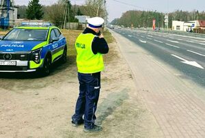 Policjanci stoją przy drodze i mierzą prędkość.
