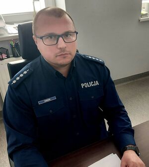 Policjant siedzi przy biurku.