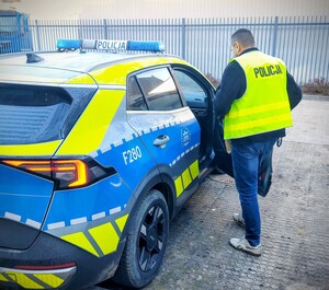 Policjant zamyka drzwi radiowozu.