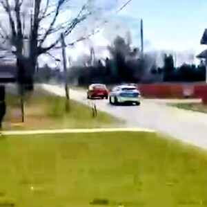 Radiowóz jedzie za czerwonym samochodem.