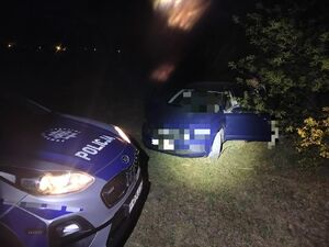 Policjant stoi przy odnalezionym mężczyźnie w samochodzie.