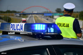 Policjant stoi przy radiowozie.