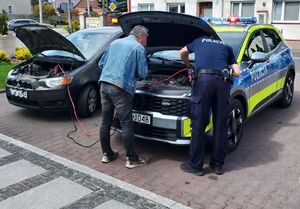 Policjant pomaga przy samochodzie z awarią.