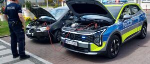 Policjant pomaga przy samochodzie z awarią.