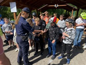 Policjanci egzaminują uczniów szkoły podstawowej na kartę rowerową.