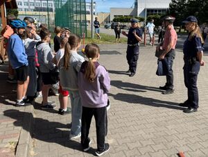 Policjanci egzaminują uczniów szkoły podstawowej na kartę rowerową.