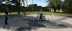 Policjanci egzaminują uczniów szkoły podstawowej na kartę rowerową.