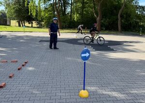 Policjanci egzaminują uczniów szkoły podstawowej na kartę rowerową.