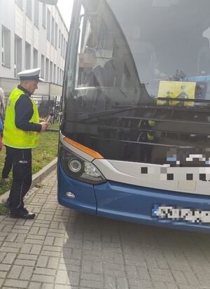 Policjant stoi przy autokarze.