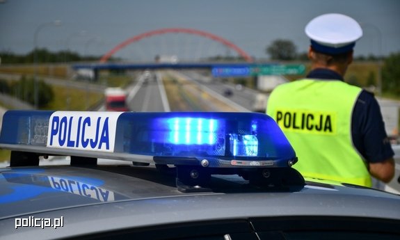 Policjant stoi przy radiowozie.