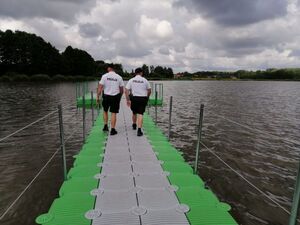 Policjanci idą pomostem nad wodą.