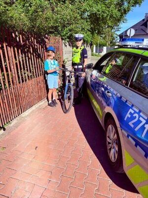 Policjanci przekazują kaski rowerzystą.