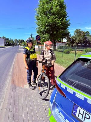 Policjanci przekazują kaski rowerzystą.