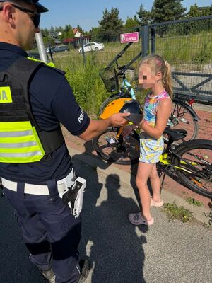 Policjanci przekazują kaski rowerzystą.