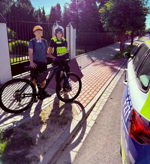 Policjanci przekazują kaski rowerzystą.
