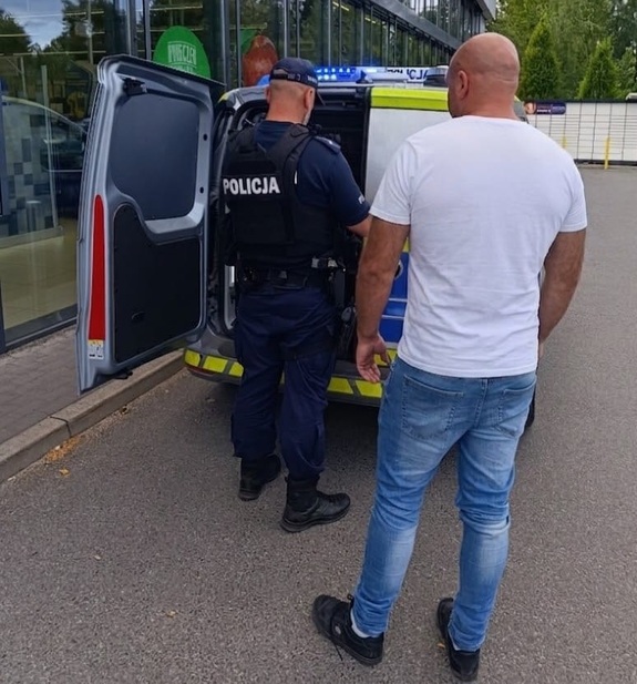 Dwóch policjantów stoi przy radiowozie.