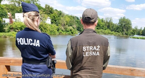 Policjantka i leśnik patrolują rejon nad wodą.