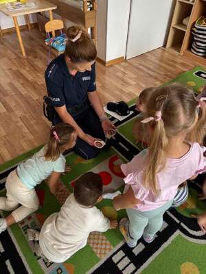 Policjantka w przedszkolu, obok niej są dzieci.