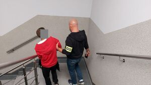Policjant prowadzi zatrzymanego mężczyznę.