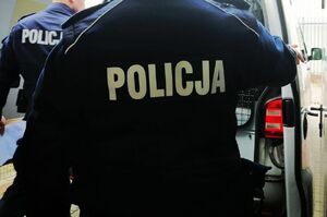 Policjanci stoją przy radiowozie.