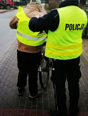 Policjant zakłada kamizelkę rowerzyście.