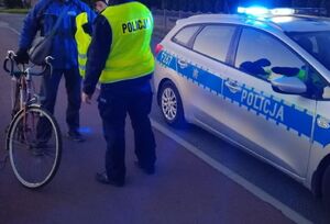 Policjant przekazuje kamizelkę rowerzyście.