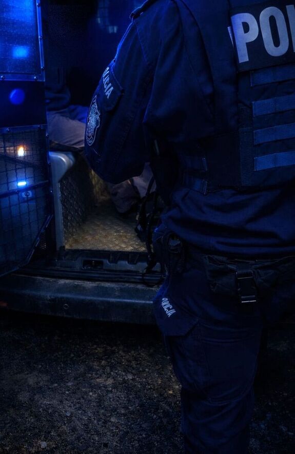 Policjant stoi przy radiowozie.