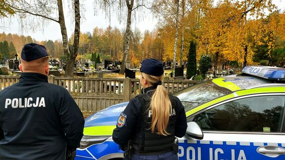 Policjanci stoją przy cmentarzu.