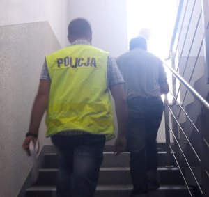 Policjant prowadzi zatrzymanego.
